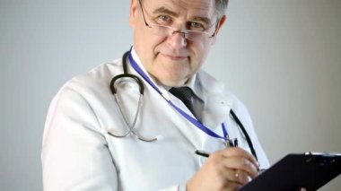 Yetişkin doktor kameraya bakar ve notlar alır. Dikkatle dinler ve hastaya tedavi önerir. İzole arka plan. Yakın çekim