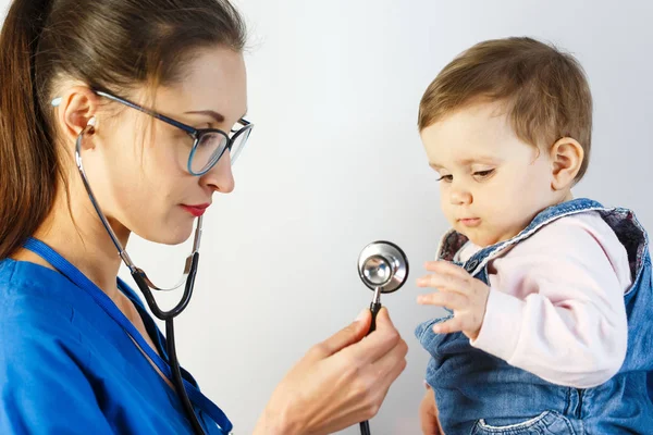 A small child on examination at the doctor looks at the stethoscope and pulls his hand to him — Stock Photo, Image