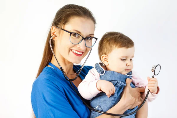 Lékař drží dítě v pažích a úsměvy, dítě se dotýká stetoskop — Stock fotografie