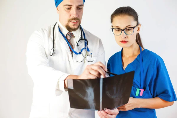 El médico le muestra a un colega una radiografía, discuten el problema. Fondo blanco — Foto de Stock