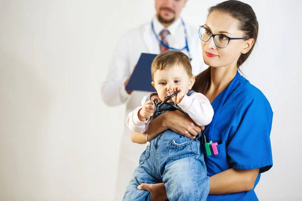 Ospalé dítě hraje s stetoskop na rukou zdravotní sestry, v pozadí je lékař. Bílé pozadí — Stock fotografie