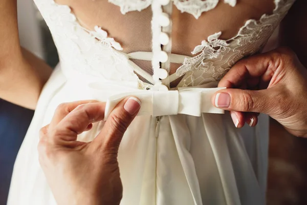 Beautiful bride dress. Witness tying a bow wedding dress on the bride.