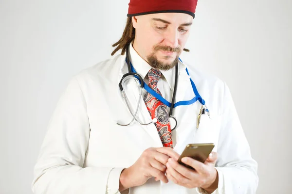 Bir doktor dreadlocks ve sakalı ile bir akıllı telefon elinde tutuyor, bir stetoskop ve resmi bir kimlikten boynunda asılı olan.