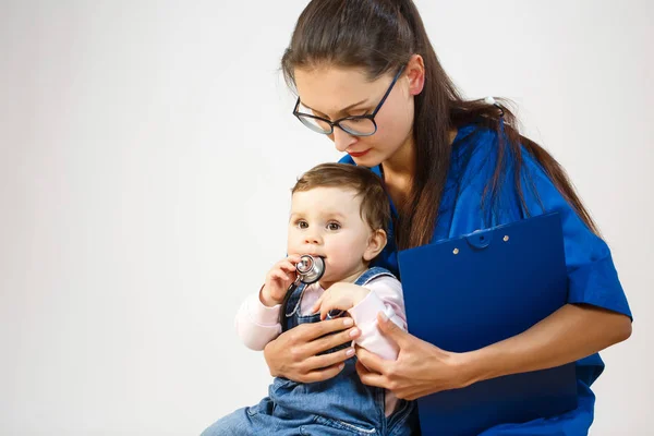 Malé dítě sedí v rukou lékaře a hraje se stetoskopem — Stock fotografie