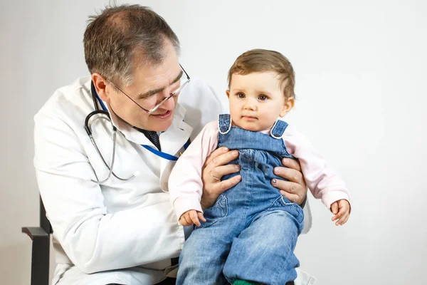 Orvos megvizsgálja a gyermek tartja a karjában — Stock Fotó