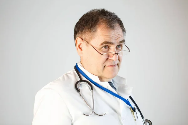 Doktor, ileri, burnunu, kaşlarını kaldırdı, bir stetoskop ve boynundan asılı bir rozet bardak ucu üzerinde görünüyor