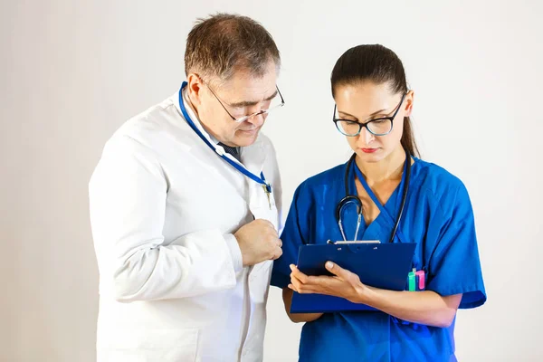 El médico sénior comprueba los resultados del tratamiento del paciente y habla con otro médico. — Foto de Stock