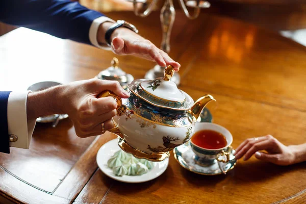 bir adam, bir kadın bir restoranda ise ahşap bir masa olarak rafine bir çanak içine çay dökülen. yakın çekim