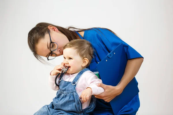 Doctor examines the child while he plays with a stethoscope Stock Image