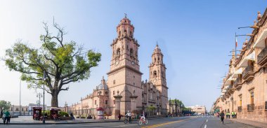 Morelia, Michoacan, Meksika - 24 Kasım 2019: Meksika 'da görülen Morelia Katedrali, ve Hükümet Sarayı, insanlar bisiklet sürüp koşuyorlar.