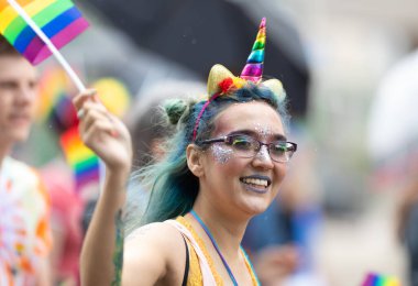 Cincinnati, Ohio, ABD - 22 Haziran 2019: The Cincinnati Pride Parade, tek boynuzlu at boynuzu giyen kadın gökkuşağı bayrağını sallıyor