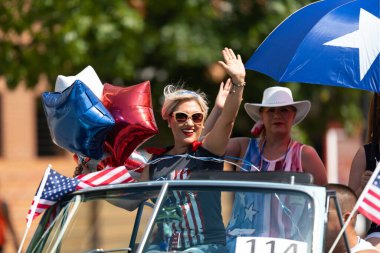 Arlington, Teksas, ABD - 4 Temmuz 2019: Arlington 4 Temmuz Geçidi, kadınlar klasik bir arabaya biniyor, tören sırasında seyircilere el sallıyorlar.