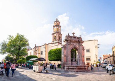 Santiago de Queretaro, Queretaro, Meksika - 24 Kasım 2019: neptün çeşmesi, Yaşam Tapınağı ve Aziz Claire 'in Kutsal Yüreği Kilisesi' nin yanında yürüyen insanlarla Francisco I Madero 'ya bakın.