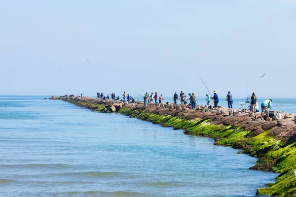Güney Padre Adası, Teksas, ABD - 19 Kasım 2019: Brazos Santiago Geçidi 'nde dalgakıranda balık tutan insanlar