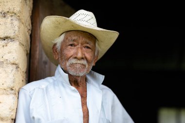 El Chorrito, Tamaulipas, Mexico, July 2, 2019: Mexican Senior, at his adobe home, waits by his door clipart