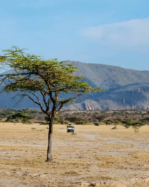 Shaba Game Reserve, Samburu, Kenya 'da manzaralı bir dağ manzarasına karşı bir safari minibüsü.