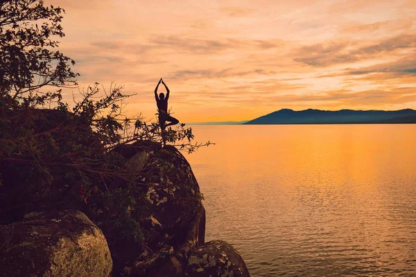 Bir uçurumda Yoga altın bir gün batımı karşı poz, Nkhata koyu, Lake Malawi