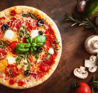 Sebze ve taze malzemelerle rustik ahşap masa üzerinde sıcak pizza 
