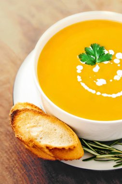 Rustik ahşap masa üzerinde beyaz kase kabak ve havuç çorbası