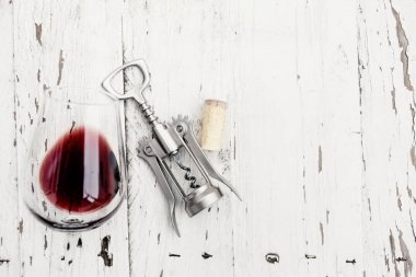 Beyaz ahşap masa üzerinde kırmızı şarap cam, şarap cork ve tirbuşon üstten görünüm
