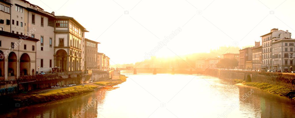 View of medieval stone bridge Ponte Santa Trinita  and Arno River from Ponte Vecchio bridge  in Florence, Tuscany, Italy at sunrise. 