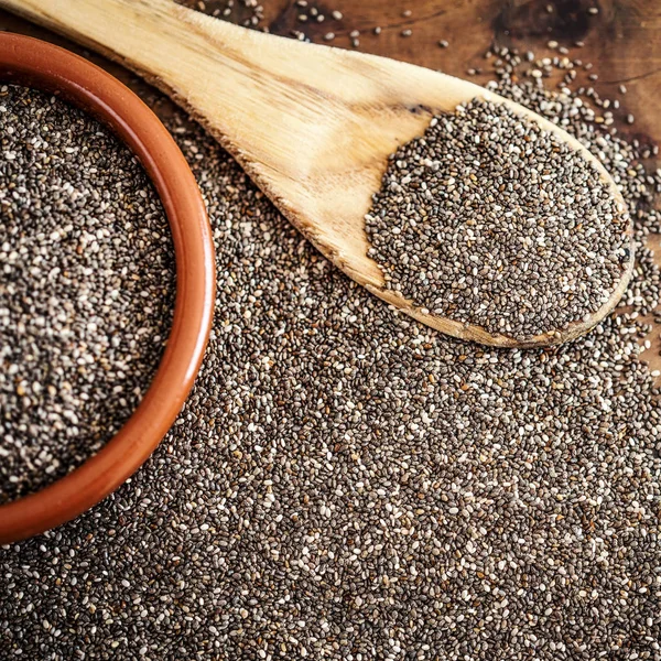 Chia seeds in wooden spoon on wood background. Bowl of Chia seeds. Top view.  Copy space