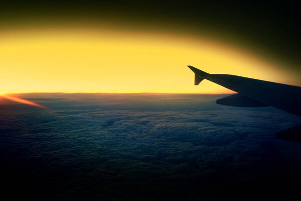 Вид из окна самолета на крыло во время заката над облаками
.