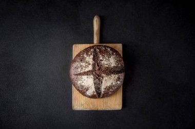 Siyah beton zemin üzerine taze ekmek. Üstten görünüm kopya alanı ile. Çavdar ekmeği kesme kurulu closeu Tarih