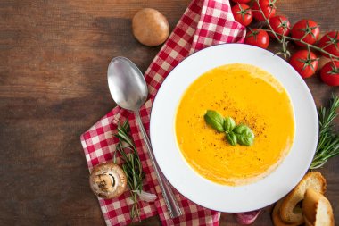 Ahşap masa üzerinde kabak çorbası ile bitki yaprakları