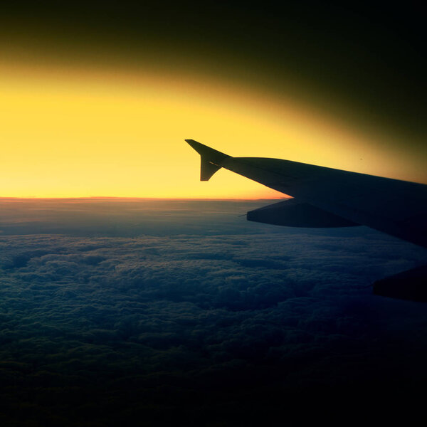 Вид из окна самолета на крыло во время заката над облаками
