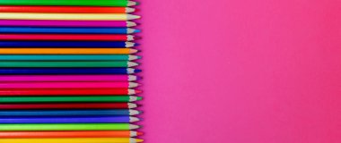 Pembe bir arka plan üzerinde üst üste kesintisiz renkli pensils. Yakın çekim. Eğitim, okul kavramı