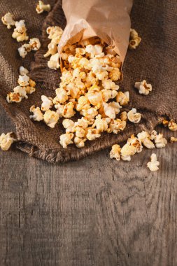Ev yapımı Kettle Mısır Popcorn bir kağıt torba. Ahşap masa üzerinde tuz patlamış mısır. Film kavramı. Fast food. Üstten görünüm. Kopya alanı