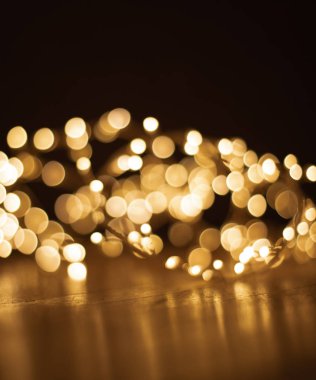 Ufuk Noel altın koyu arka plan üzerinde ışıklar. Ahşap zemin, boşaltmak üzerinde Noel çelenk