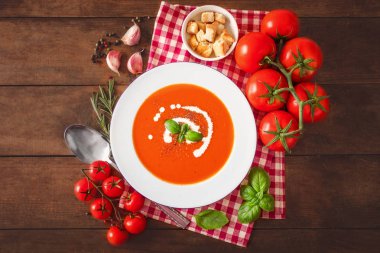 Taze domates, fesleğen yaprakları ve sarımsak ahşap masa üzerinde domates çorbası kompozisyonu.