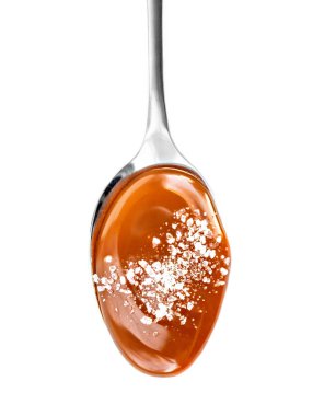  Beyaz arka plan üzerinde izole tuzu kaşıkla Karamel sosu. Tuzlu kurabiye karamel akan