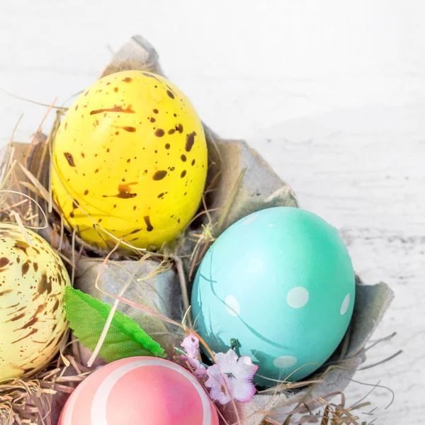 Påskägg i ägg cartoon låda på vit rustik trä bakgrund — Stockfoto