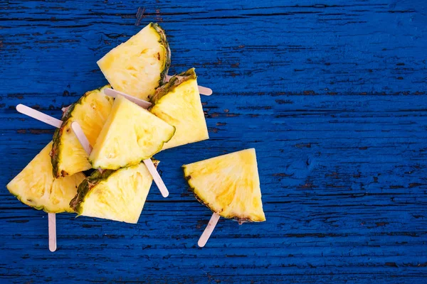 Pineapple  slice popsicles on blue rustic wood background. Summe — Stock Photo, Image