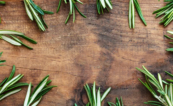 Frame made of fresh rosemary herb on  wooden board. Top view. Co — Stock Photo, Image