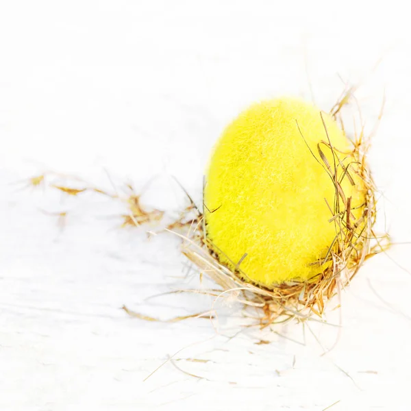 Uova di Pasqua in un nido di vimini su sfondo di legno bianco con co — Foto Stock
