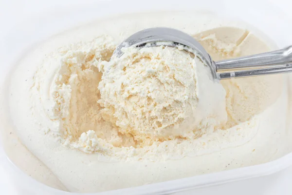 Vanilla ice cream with a scoop in  container as background. Macro. Scooped out ice-cream,  top view.