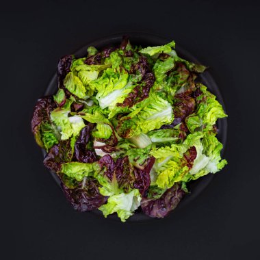 Yeşil ve mor marul salatası taze bahar kopya alanı kara tahta zemin üzerine siyah bir kase içinde bırakır. Diyet menüsü. Üstten Görünüm.