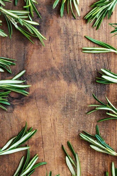 Frame made of fresh rosemary herb on  wooden board. Top view. Co — Stock Photo, Image