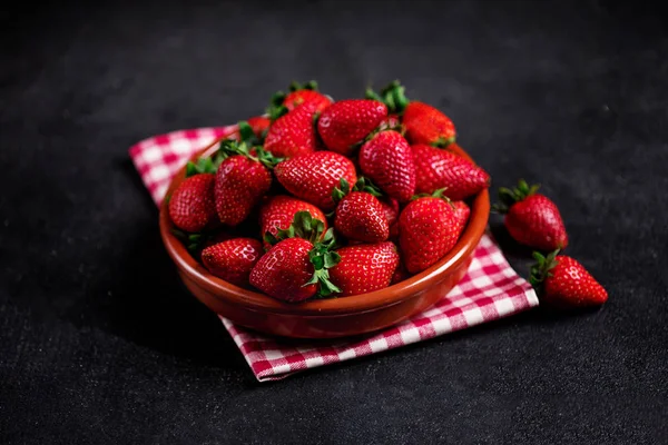 Aardbei heap. Verse aardbei in een klei kom op een donkere BAC — Stockfoto