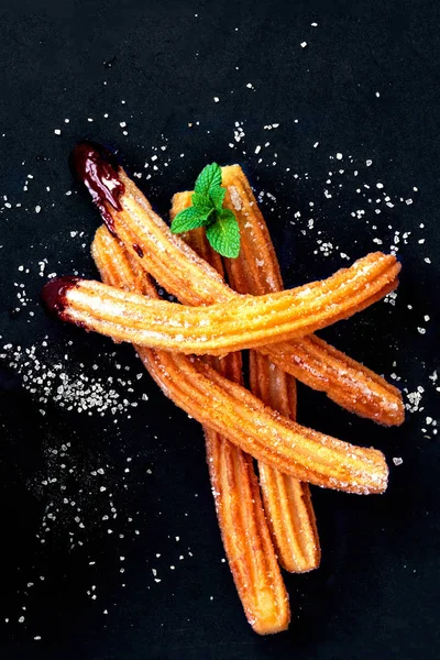 Churros con azúcar y salsa de chocolate sobre fondo negro. Ch — Foto de Stock