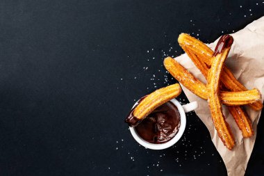 Siyah bir backgrou üzerine çikolata sosu batırılmış şeker ile Churros