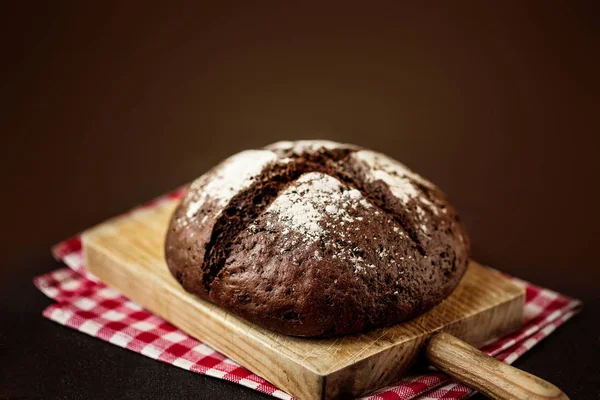 Koyu rustik wo üzerinde ahşap kesme tahtası üzerinde taze pişmiş ekmek — Stok fotoğraf