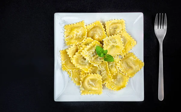 Fresh ravioli on a white plate  over  dark background, top view. — Stock Photo, Image