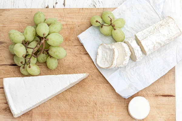 Bandeja de queso con diferentes quesos y uvas en madera blanca —  Fotos de Stock