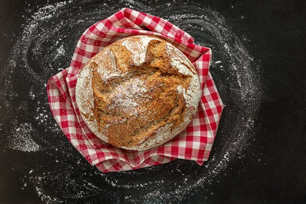 Siyah arka planda taze ekmek somun. Kırmızı damalı şekerlemede ekmek — Stok fotoğraf