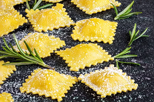 Raviolli pasta with Spinach leaves, flour and herbs on black bac — Stock Photo, Image